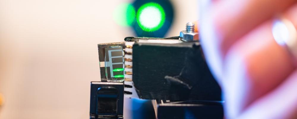 Feng Gao och Huotian Zhang testar effektiviteten hos en liten bit av en organisk solceller med grön laser. Av: Olov Planthaber/Linköpings universitet. Upphovsrätt: Linköpings universitet